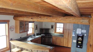 Eine rustikale Küche mit Holzschränken, einer Bar mit Hockern und einem Herd.