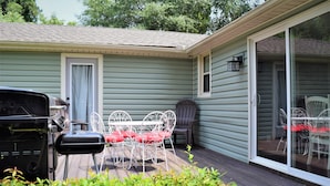 A patio with a grill, a table with chairs, and a sliding glass door leading to an indoor area. - Moonshine Cottage - Time to GOLF! (Pinehurst)