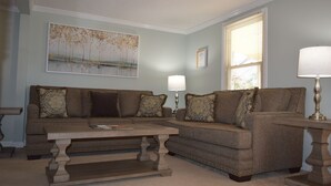 A living room with two sofas, a coffee table, a lamp, and a painting on the wall. - Moonshine Cottage - Time to GOLF! (Pinehurst)