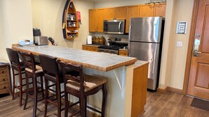 A kitchen with a central island, wooden cabinets, stainless steel appliances, and a built-in oven. - In the heart of Avon -walk to restaurants & gondola!  Immaculate 2bed/2bath (Avon)