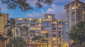 Un hôtel à plusieurs étages doté de balcons, d’un restaurant situé au rez-de-chaussée et d’un espace de stationnement.