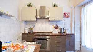 Una cucina compatta con mobili bianchi, forno in acciaio inossidabile e piano di lavoro in granito.