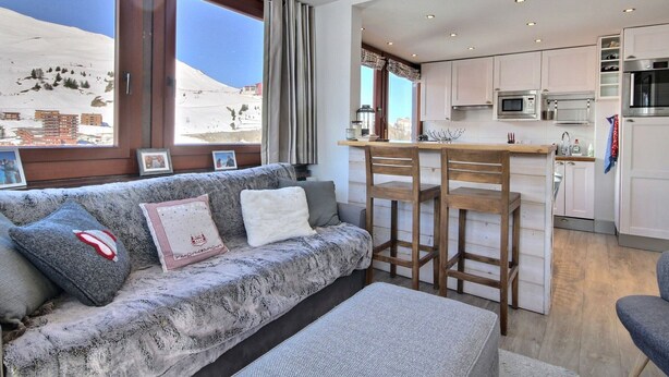 A living room with a sofa, a coffee table, and a view of a snowy landscape through large windows. - Renovated apartment 64m², 6 pers, balcony, Wi-Fi, slopes (La Plagne)