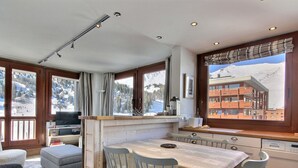 A modern kitchen with a dining area, large windows with mountain views, and a cozy seating arrangement. - Renovated apartment 64m², 6 pers, balcony, Wi-Fi, slopes (La Plagne)