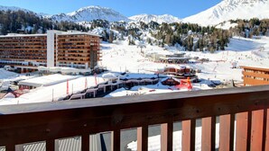 A hotel with multiple floors, a ski resort in the background, and snow-covered mountains. - Renovated apartment 64m², 6 pers, balcony, Wi-Fi, slopes (La Plagne)