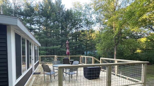 A wooden deck with outdoor furniture, a covered table, and a fenced area.