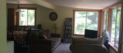 A living room with a sofa, a coffee table, a bookshelf, and a television.