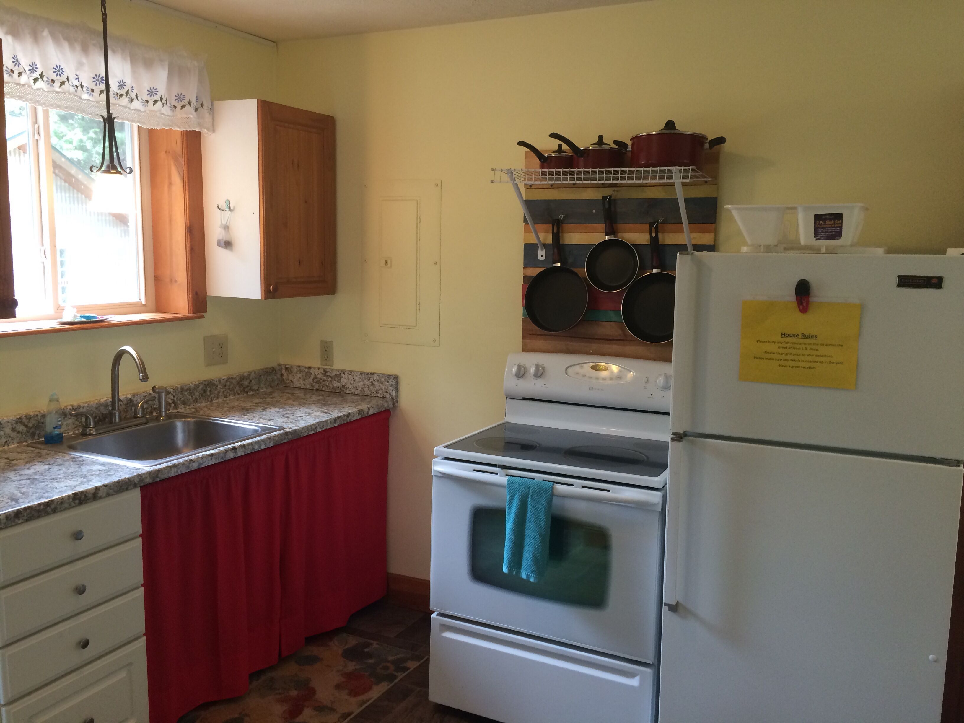 A kitchen with a granite countertop, a stainless steel sink, a white stove, and a refrigerator.