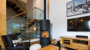 A modern living room with a fireplace, a comfortable seating area, and a television mounted on the wall.