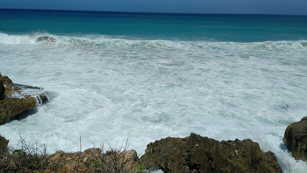Une vue sur la côte, avec des vagues qui s’écrasent contre des rochers.