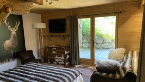 A wooden cabin bedroom with a bed, a dresser, a television, and a large window. - Prestigious chalet ski in ski off at Megéve (Megève)