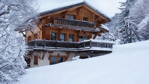 A wooden chalet with multiple balconies, surrounded by snow-covered trees. - Prestigious chalet ski in ski off at Megéve (Megève)