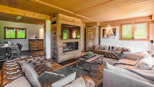 A cozy living room with a fireplace, leather sofas, and a dining area with a long table. - Prestigious chalet ski in ski off at Megéve (Megève)