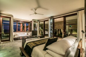 A spacious bedroom with a large bed, a desk, a sofa, and a television. - PANDAWA BEACH CLIFF EDGE ABSOLUTE OCEAN VIEW VILLA BALI 5 STAR LUXURY 3 BEDROOMS (kutuh)