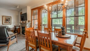 A dining area with a wooden table and chairs, a chandelier, and a fireplace.