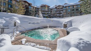 A pool area surrounded by snow with a clear sky.