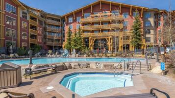 A hotel with a pool area, outdoor seating, and a view of the building's exterior.