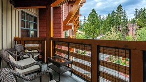 A balcony with wicker furniture and a view of a forested area.