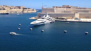 Eine große Yacht liegt im Hafen vor einem historischen Gebäude.