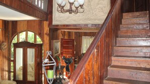 Un escalier en bois, un lustre, un meuble et une chaise.