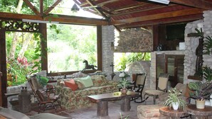 Un espace extérieur abrité, doté d’un mur en pierre, de mobilier en bois et de plantes en pot.
