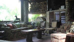 Un salon chaleureux avec une cheminée en pierre, une table en bois et des sièges confortables, notamment un canapé et des fauteuils.