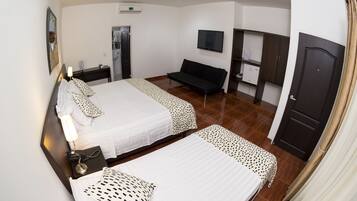 Quarto de hotel com duas camas, um banco, uma televisão, uma escrivaninha e um guarda-roupa.