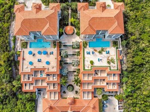 Vue aérienne d’un complexe hôtelier composé de deux bâtiments, chacun doté d’une piscine, d’espaces de détente et d’une cour intérieure.