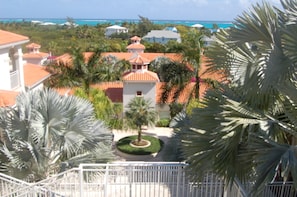 A resort with a central building surrounded by palm trees and a view of the ocean. - AquaBLU Ocean View Studio (Providenciales)