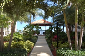 A pathway leading to a gazebo surrounded by lush greenery and palm trees. - AquaBLU Ocean View Studio (Providenciales)