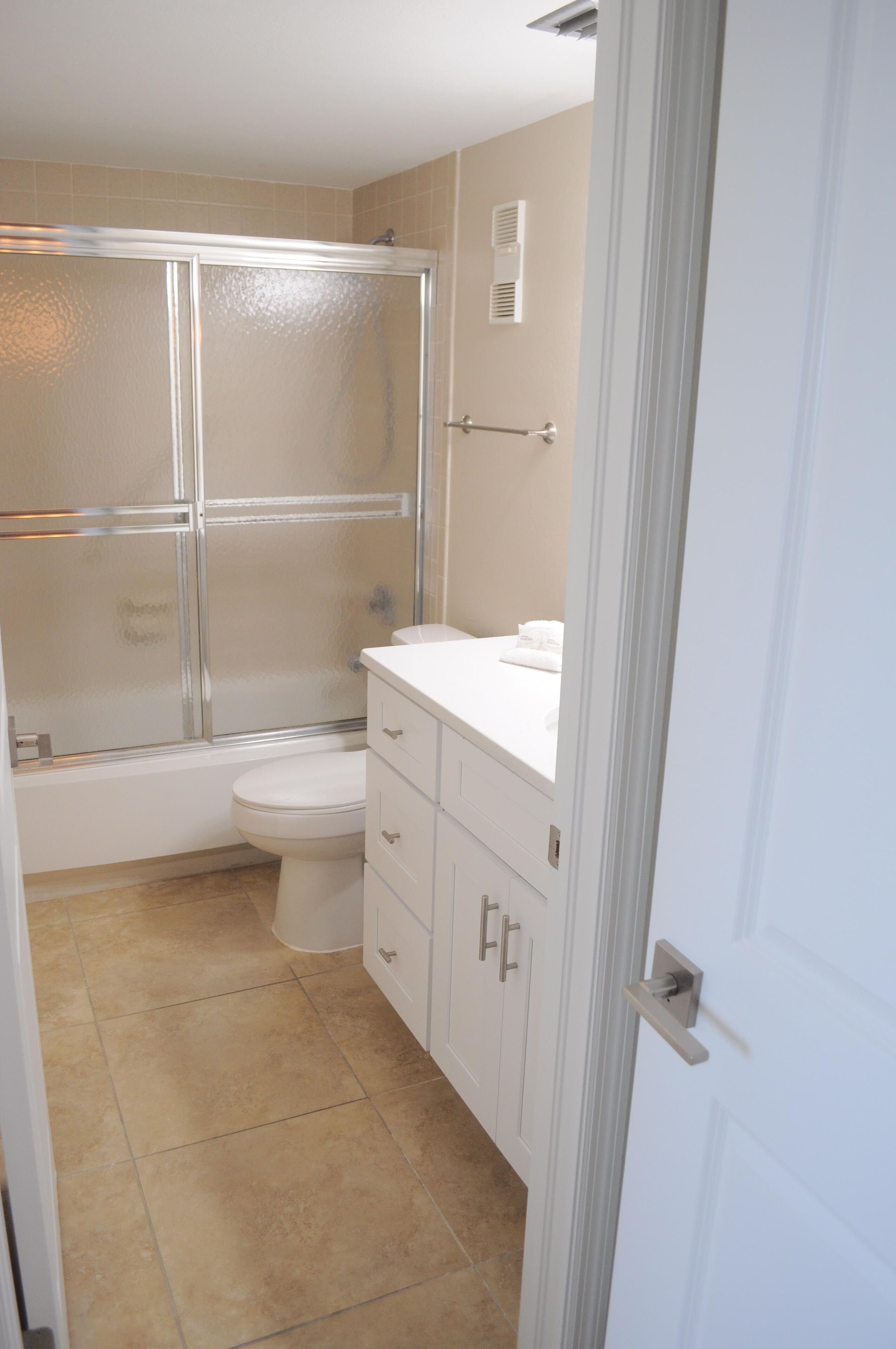 Une salle de bain avec une douche à parois de verre, des toilettes et un meuble-lavabo doté de tiroirs et d’un miroir.