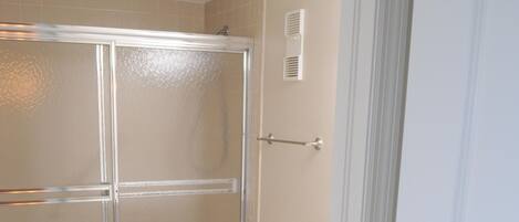 Une salle de bain avec une douche à parois de verre, des toilettes et un meuble-lavabo doté de tiroirs et d’un miroir.