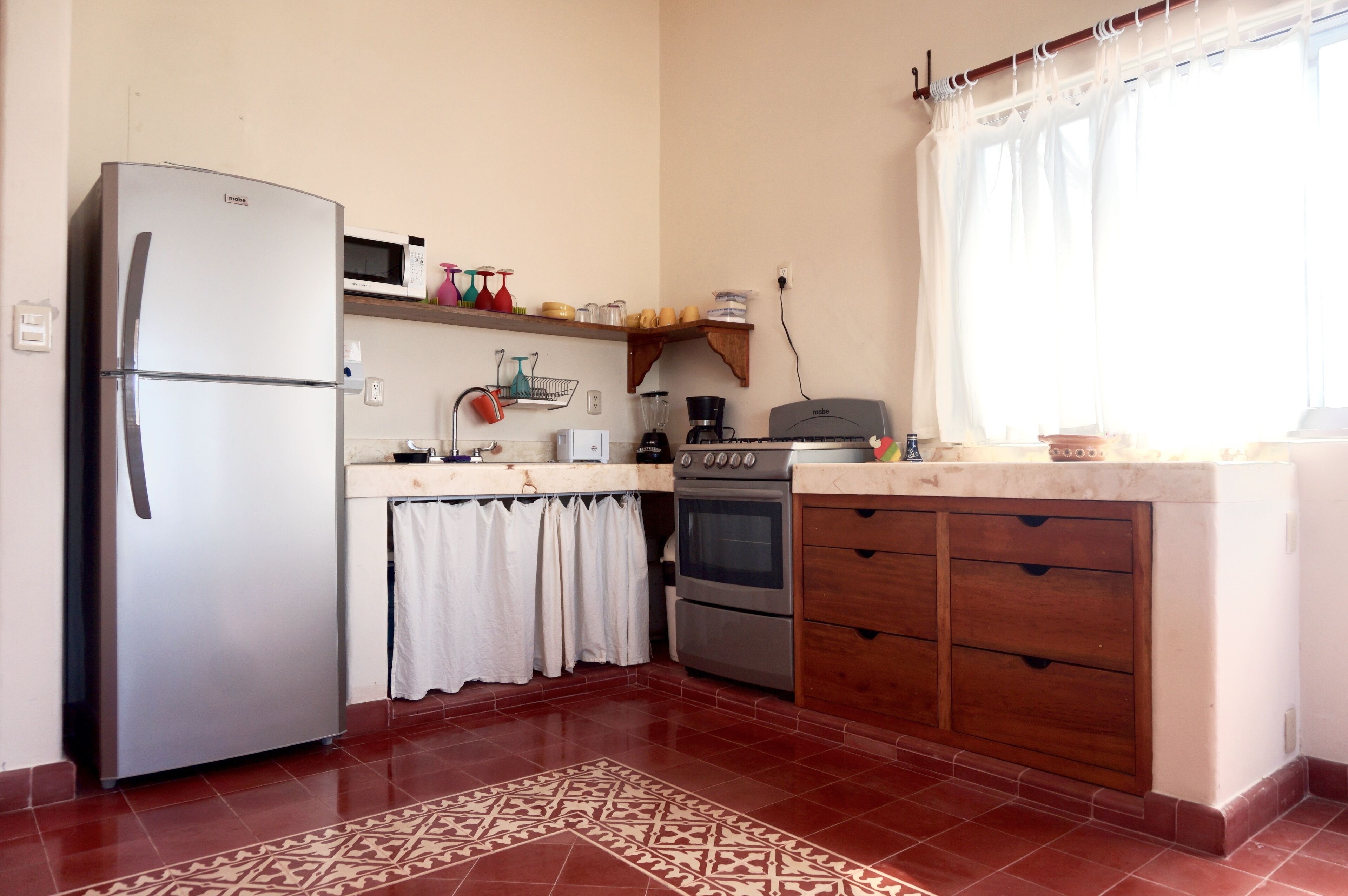 Une cuisine équipée d’un réfrigérateur, d’un four à micro-ondes, d’un four traditionnel et de meubles de rangement en bois.