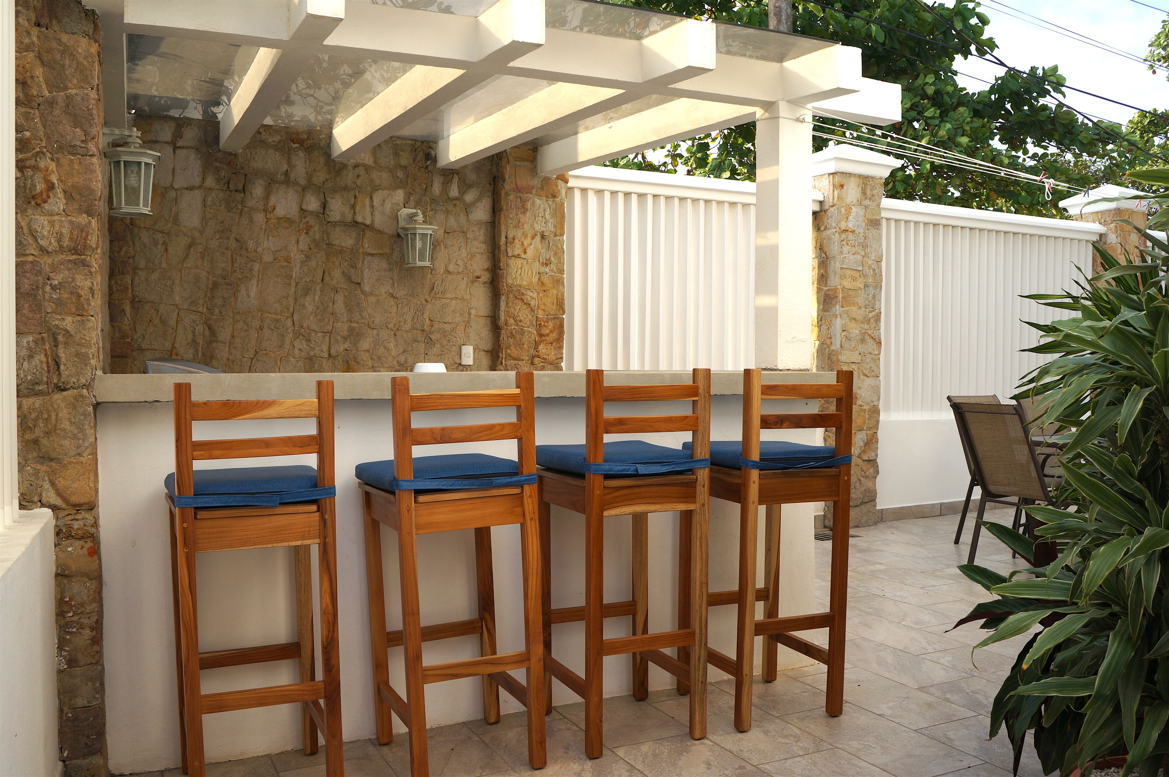 A patio area with wooden chairs and a stone wall.
