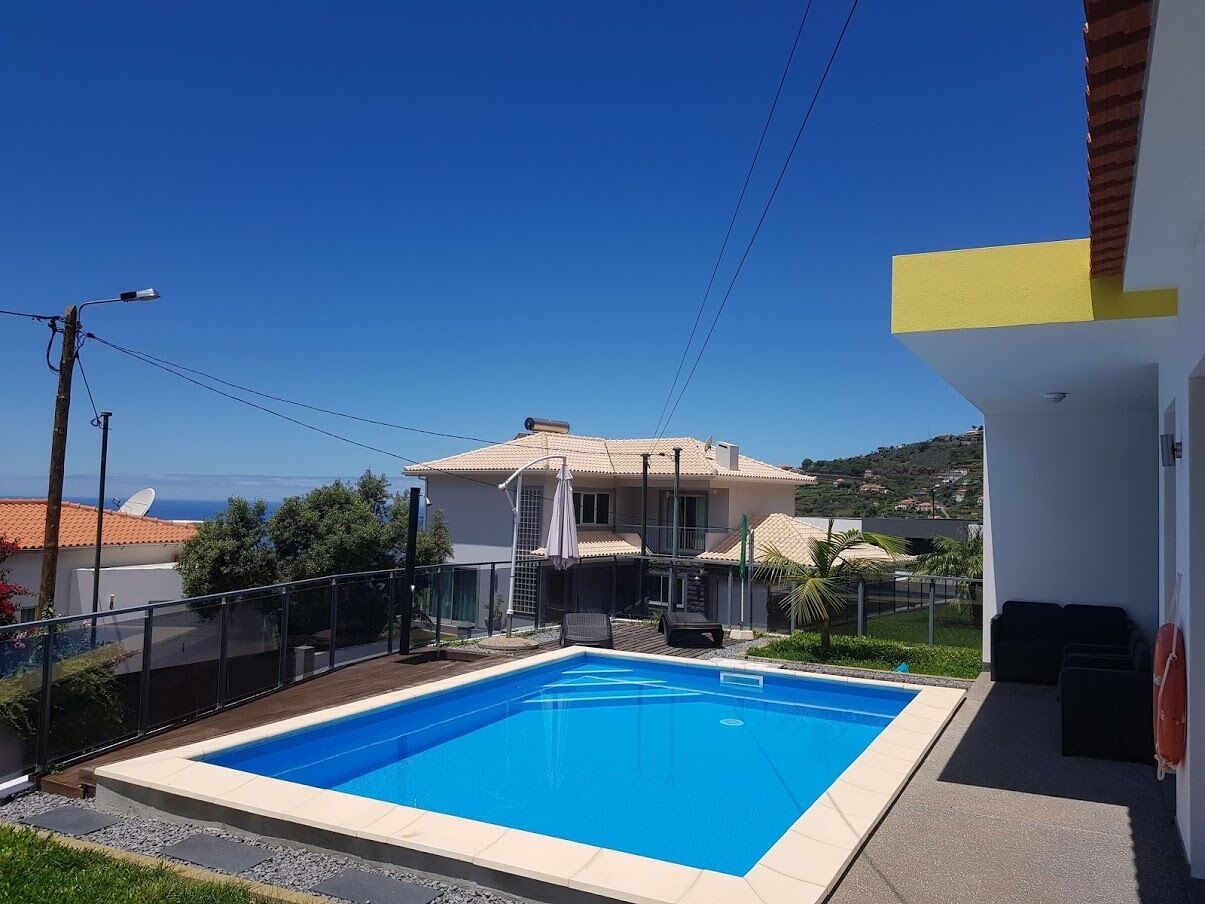A swimming pool with a view of a house and hills in the background.