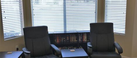 Une pièce comprenant deux fauteuils, une petite table et une bibliothèque remplie de livres.