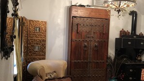 A cozy living room with a patterned sofa, a wooden door with metal studs, a chandelier, and a black stove.