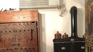 A kitchen with a wooden door, a stove, and a blue vase with dried plants.