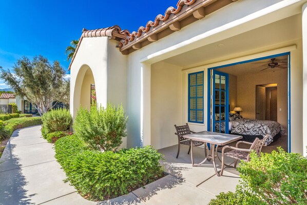 A patio with a table and chairs, a covered seating area, and a view of the interior. - Near Pool! Best Location! Single Story Poolside Villa across from Clubhouse, Pet Friendly! (C72) (La Quinta)