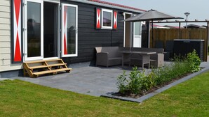 Un patio con mesa y sillas, un banco de madera y una zona de estar cubierta.