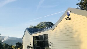 A modern building with a sloped roof, large windows, and a gravel driveway with stepping stones. - Luxury Holiday Home with Hot Tub,  Pet & Family friendly in the Yorkshire Dales  (Eastby)