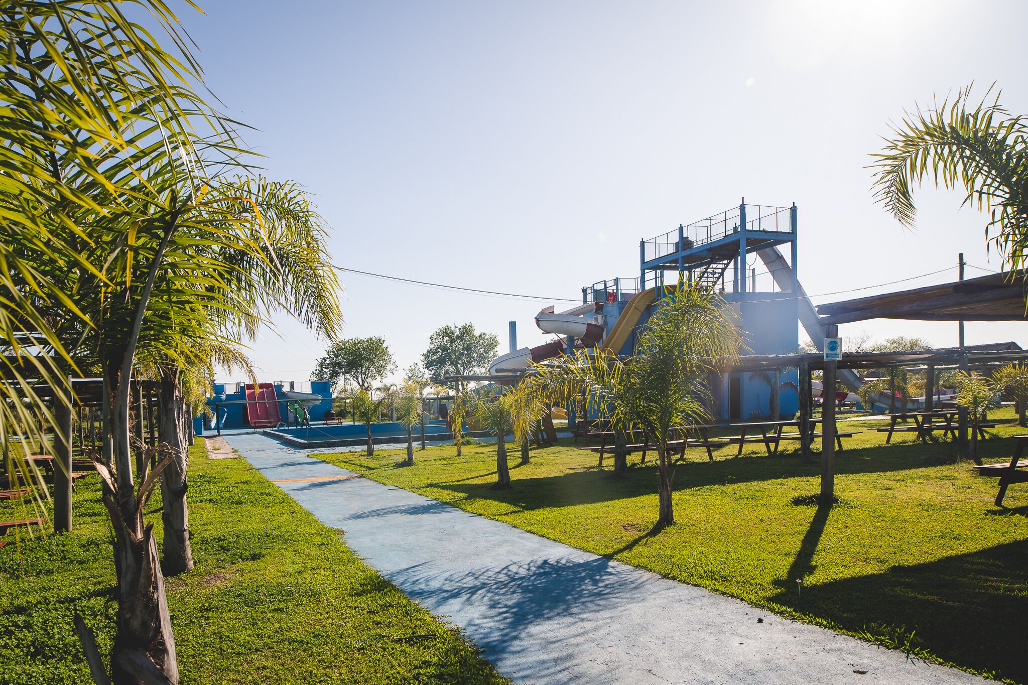 Un parque con un área de juegos, mesas de picnic y un tobogán.