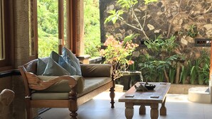 Una habitación acogedora con un sofá de madera, una mesita de centro y una pared de piedra con plantas.