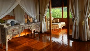 Una habitación con una cama de madera, un tocador decorativo y vistas a la vegetación.