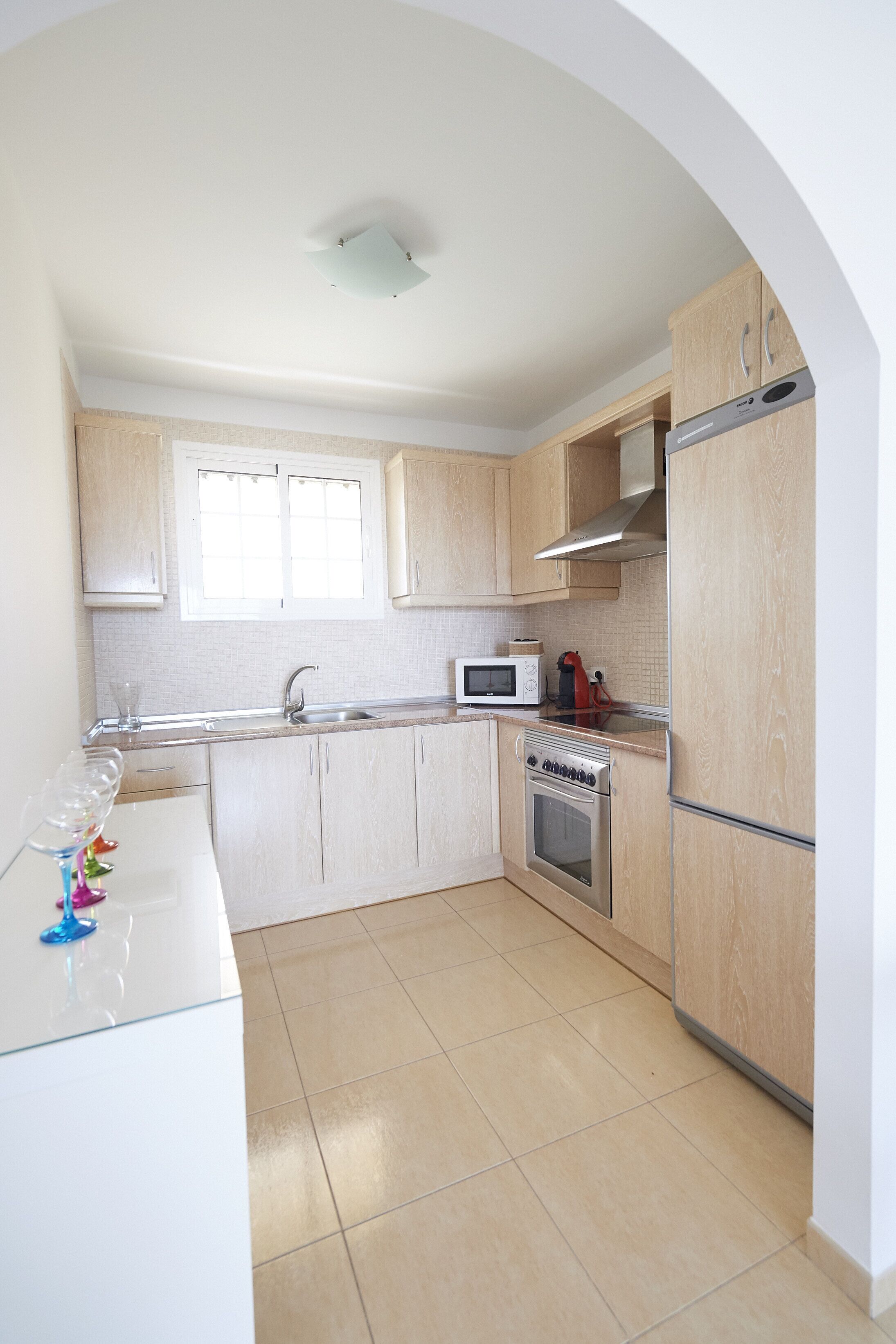Une cuisine avec des meubles de rangement en bois, un four à micro-ondes, une cuisinière et un réfrigérateur.
