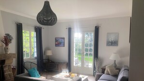 Ein Wohnzimmer mit zwei Sofas, einem Couchtisch, einem Kamin und einem großen Fenster mit Vorhängen.