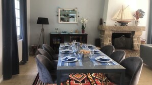 Ein Esszimmer mit einem langen Tisch, gedeckt für sechs Personen, einem Steinkamin und einem Spiegel an der Wand.