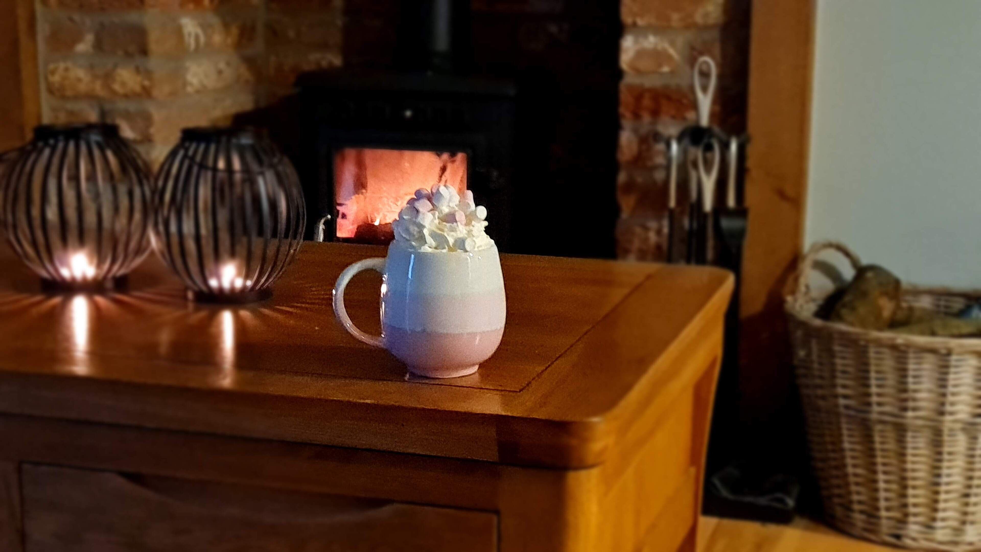 A mug with whipped cream and marshmallows on a wooden table.