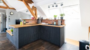 Une cuisine moderne avec des meubles de couleur sombre, un plan de travail en bois et une grande fenêtre.