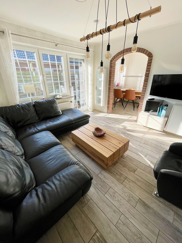 A modern living room with a sectional sofa, a wooden coffee table, and a TV.